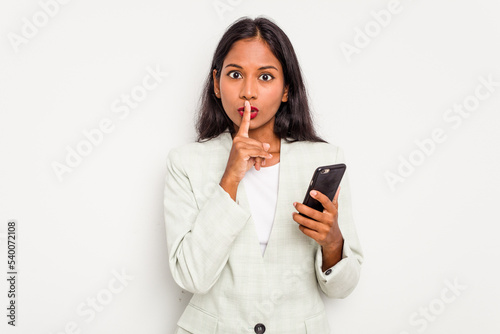 Young business Indian woman holding a mobile phone isolated on white background keeping a secret or asking for silence.