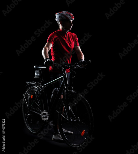 Fototapeta Naklejka Na Ścianę i Meble -  Low key side view silhouette of a mountain biker with his bicycle in a black studio