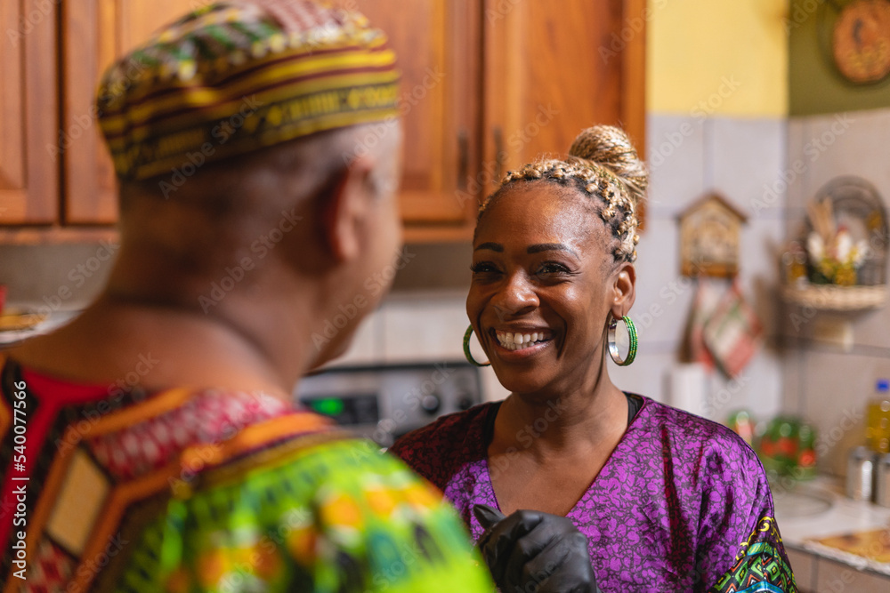 Imagen horizontal de una mujer afrocaribeña platicando muy sonriente  con su esposo en el interior de su casa. 