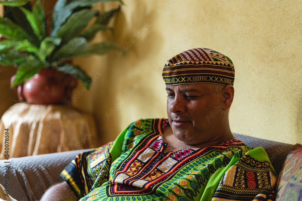 Obraz premium Imagen horizontal de cerca de un hombre adulto latino en el interior de su casa utilizando una camisa y gorro caribeño. 