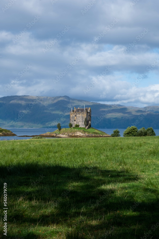 A small castle on a tiny island in Sotland. Castle Stalker on loch linnhe, coastline of argyll. A four-storey tower house/keep on a loch on a tidal islet. 