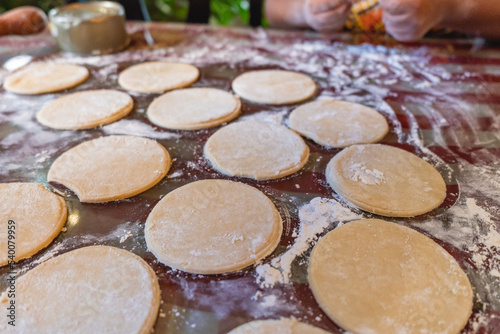 Imagen horizontal muchos trozos de masa con forma circular sobre una mesa listos para preparar unos deliciosos bocadillos caribeños. 