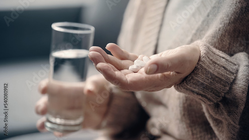 partial view of senior woman with dementia holding pills and glass of water. © LIGHTFIELD STUDIOS