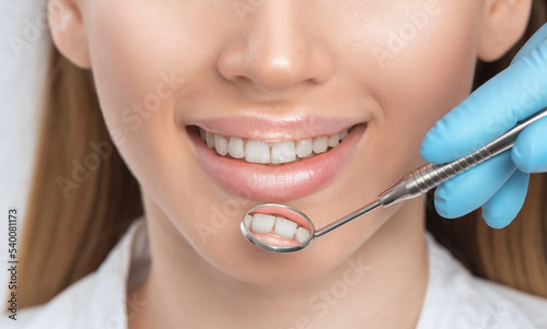 A dentist doctor treats caries on a tooth of a young beautiful woman in a dental clinic. Tooth filling.