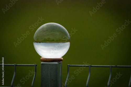 Bild auf Leinwand Closeup of a perfect sphere crystal on a metal post and reflecting the surroundi
