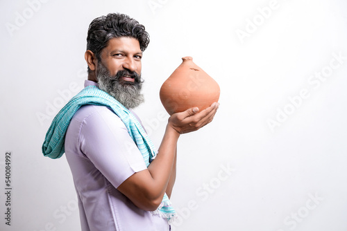 Indian farmer holding clay piggy bank in hand on white background.