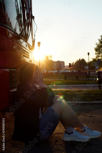 A woman sits on the asphalt and cries in the sunset photo