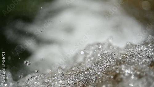 Closeup of water drops from a waterfall in the mountains (slow motion, bokeh) photo