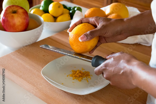 Bild auf Leinwand Black woman, African American woman hands zesting a orange with fine grater on a