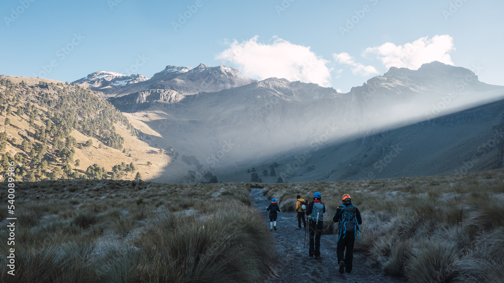 Fototapeta premium Group of hikers walking in grassland with mountains in the background. Iztaccihuatl