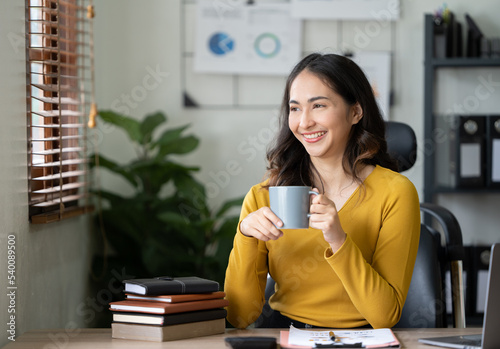Asian businesswomen use notebooks and businesswomen smile happily while eating coffee. Take breaks during work