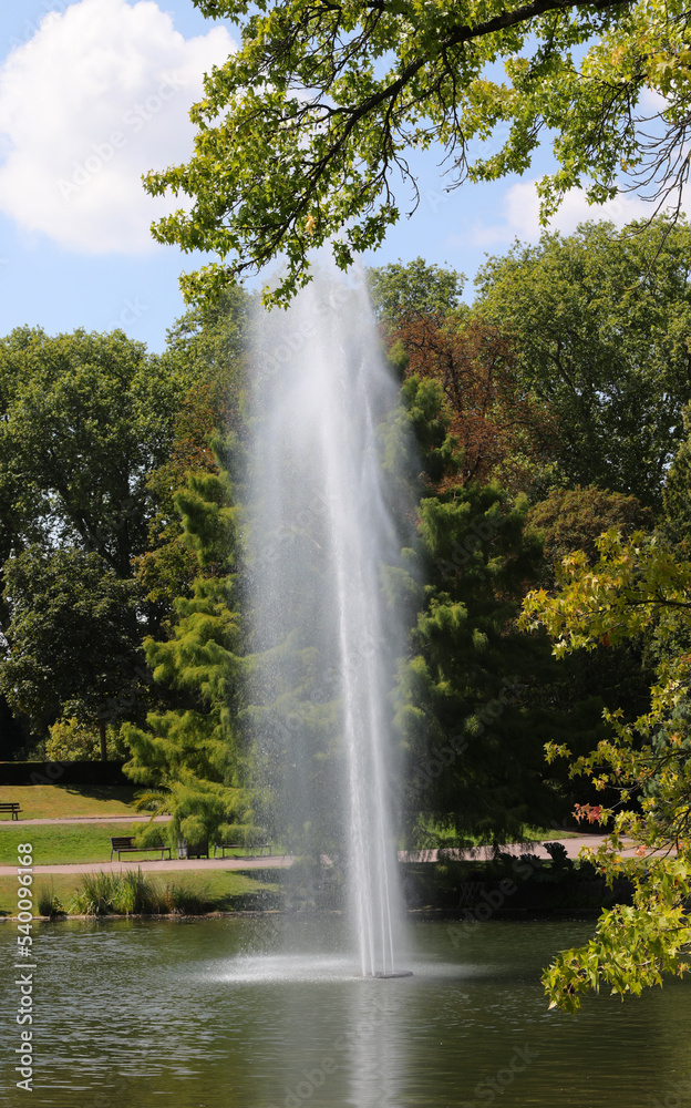 high jet of water from the fountain in the middle of the pond in the park