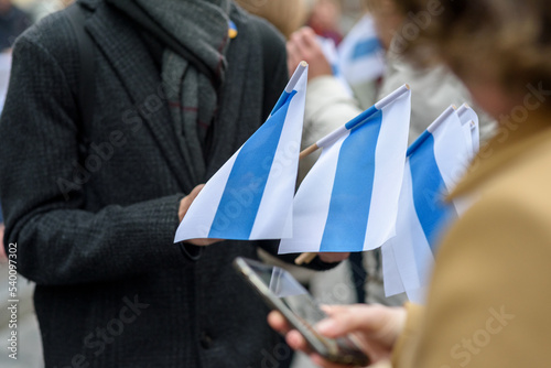 Person holding white-blue-white flags. Symbol of opposition to Russian invasion of Ukraine, used by Russian anti-war protesters