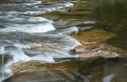 Wasser im Fluss fließt über Steine. Langzeitbelichtung mit Bewegungsunschärfe