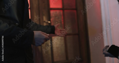 Close up of businessman in black suit giving to concierge pass card for entering luxury casino with vip service. Lifestyles of celebrity people.