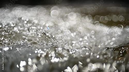 Bokeh effects from sunlight on the water from a mountain stream (slow motion) photo