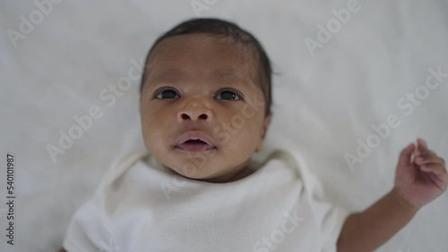 Closeup portrait of African black new born baby sleeping sweet dream on bed over white background. Healthy newborn child take awake looking. Family love newborn healthcare medical concept