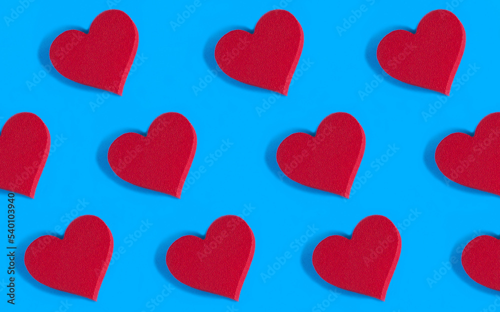Red hearts on the blue background. Pattern. Flat lay.