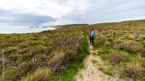 hiker girl with a backpack walks along paradise bay on rottnest island, near perth in western australia, paradise beaches of western australia