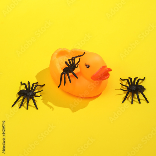 Creative layout with rubber duck and spiders on bright yellow background. Visual trend. Halloween concept. Minimalistic aesthetic still life with shadow. Fresh idea