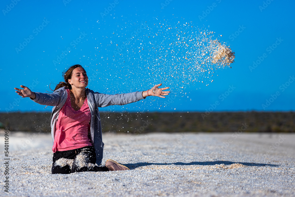 A beautiful girl plays with seashells on the famous shell beach in western australia, sunset on shell beach in francois peron national park A beautiful girl plays with seashells on the famous shell beach in western australia, sunset on shell beach in francois peron national park