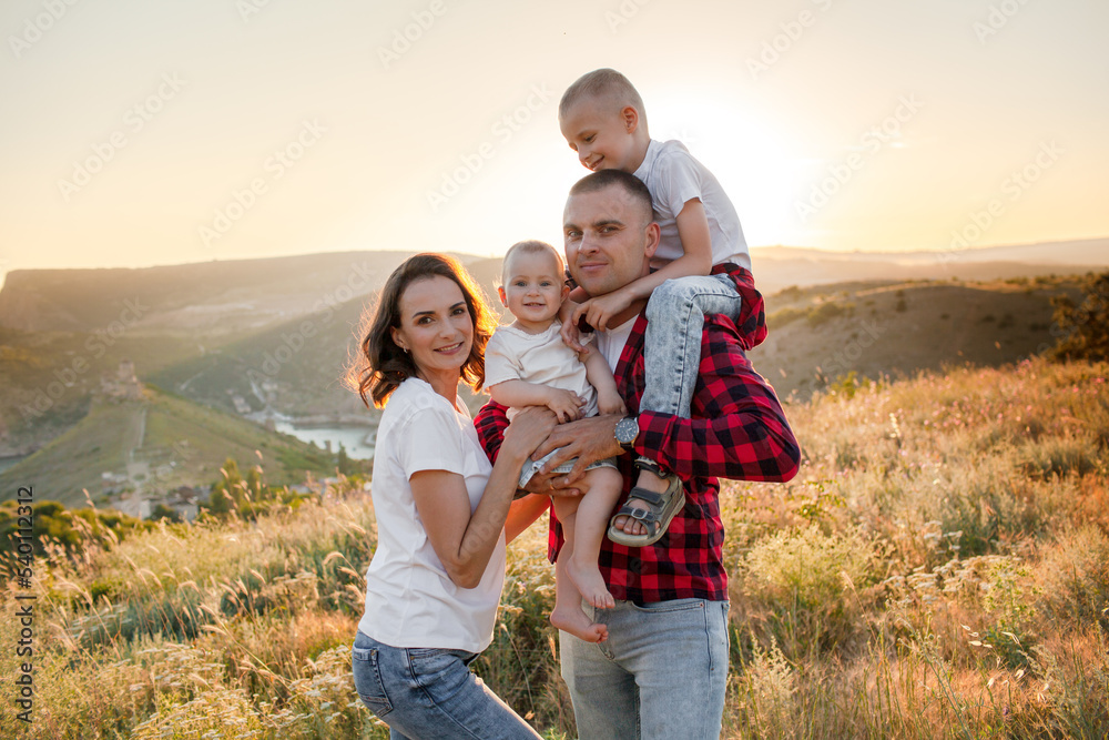 Happy family spending time together in the nature, mother father daughter and son have fun, playing with kids in vacation against the background the grass, mountain and sunset Happy family spending time together in the nature, mother father daughter and son have fun, playing with kids in vacation against the background the grass, mountain and sunset