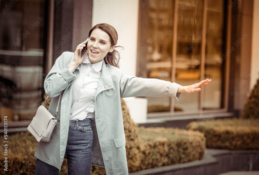 Fototapeta premium Cute lady catches car in city and talks on the phone