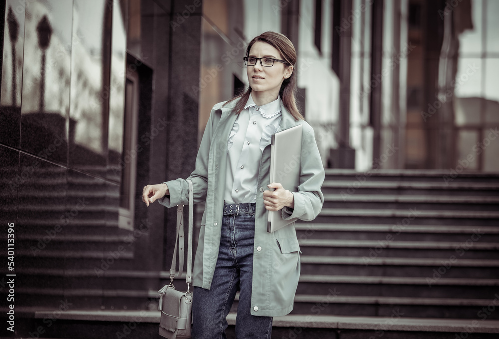 Pretty business woman comes down the steps with laptop. Lifestyle