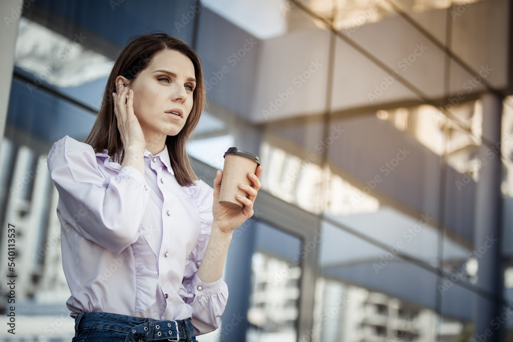 Cute business woman talking on wireless headphones on the background of the business center Cute business woman talking on wireless headphones on the background of the business center