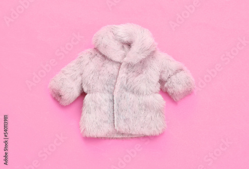 Doll fur coat on pink background. Minimalism fashion layout. Top view. Flat lay