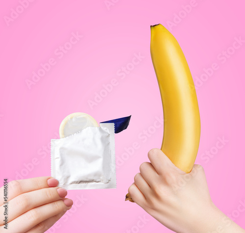 Yellow banana and female hand holding a package with a condom. photo