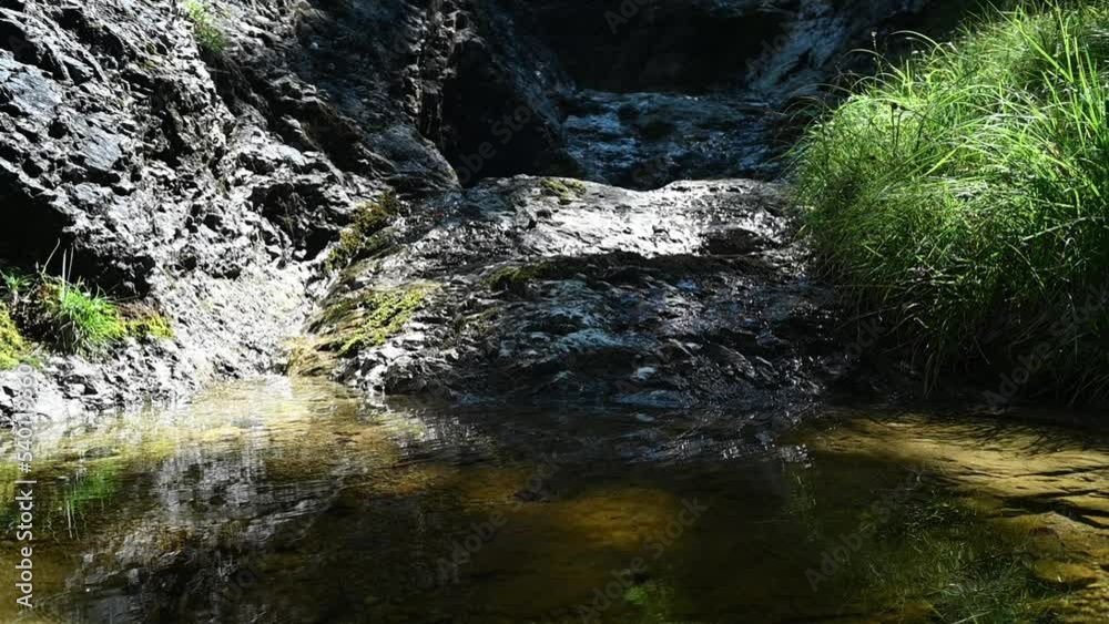 A little rivulet flows into a pool in the mountains (slow motion)