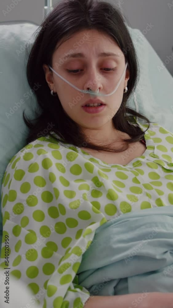 Vertical video: Sick patient lying in bed talking with practitioner doctor explaining disease symptom. Medic specialist writing disease treatment on clipboard discussing sickness expertise working in
