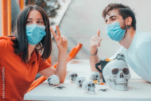 Friends boy and girl taking a selfie in medical masks while making Halloween skull gang decorations