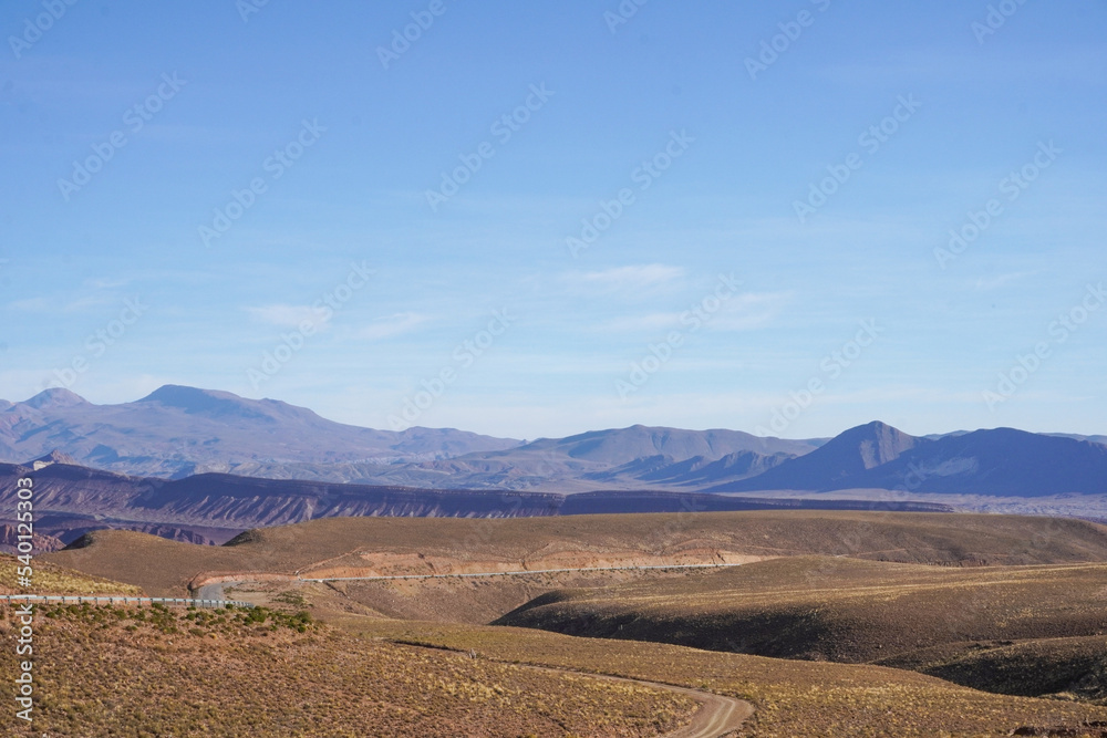 Paisaje de serranía (mountain range) camino entre Uyuni y Potosí (Potosi)  con carretera en el medio y montañas de fondo 