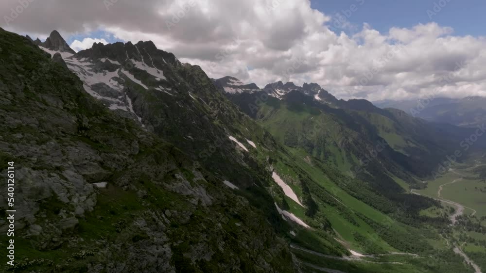 Close-up of a rocky slope covered with stone cliffs, deep cracks and small waterfalls on the rocks of the Caucasus Range. View of the mountain valley Close-up of a rocky slope covered with stone cliffs, deep cracks and small waterfalls on the rocks of the Caucasus Range. View of the mountain valley