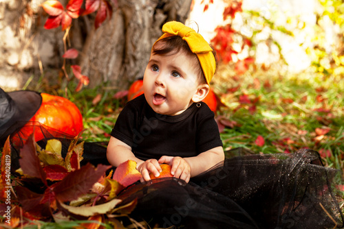 Female toddler in black dress against the Halloween pumpkin