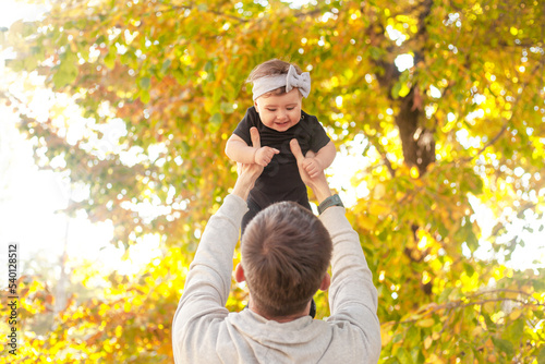 Happy father play with the baby. The man holding the toddler in the hands and have fun laughing, throwing the child up as if the kid flying