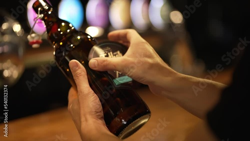 The man holds a bottle of light beer in his hands and sticks a name label on it photo