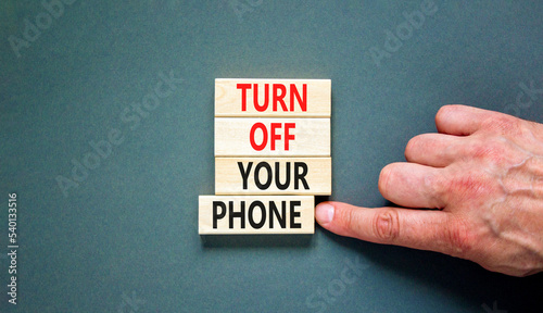 Turn off your phone symbol. Concept words Turn off your phone on wooden blocks. Beautiful grey table grey background. Businessman hand. Business psychological turn off your phone concept. Copy space