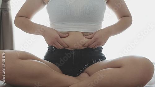 Beautiful fat woman with tape measure She uses her hand to squeeze the excess fat that is isolated on a white background. She wants to lose weight, the concept of surgery and break down fat under the