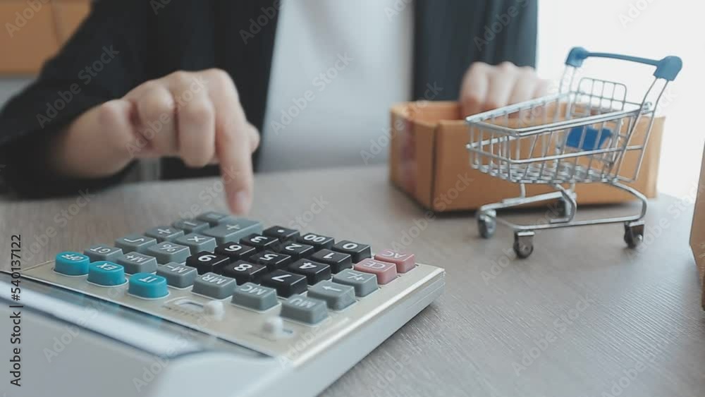 Young Asian business woman using mobile phone call receiving purchase order and check product in stock, work at home office. Small business SME online market delivery, lifestyle freelance concept.