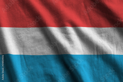 Luxembourg flag with big folds waving close up under the studio light indoors. The official symbols and colors in banner photo