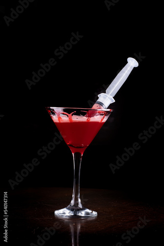 halloween party with drink in martini glass and blood syringe in glass photo