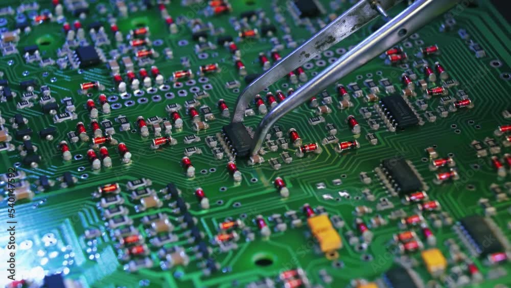 Human and modern technology concept. Robots versus workers. Closeup shot of silver tweezer tool glueing electric pieces onto printed circuit board. High quality 4k footage Human and modern technology concept. Robots versus workers. Closeup shot of silver tweezer tool glueing electric pieces onto printed circuit board. High quality 4k footage