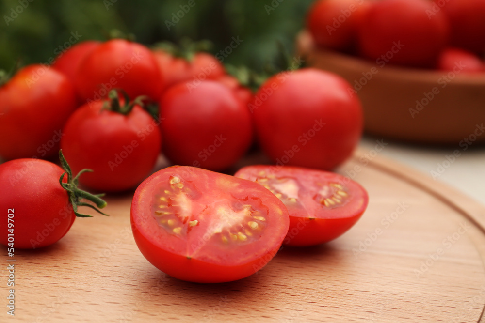 Cut and whole red tomatoes on wooden board against blurred background, closeup Cut and whole red tomatoes on wooden board against blurred background, closeup