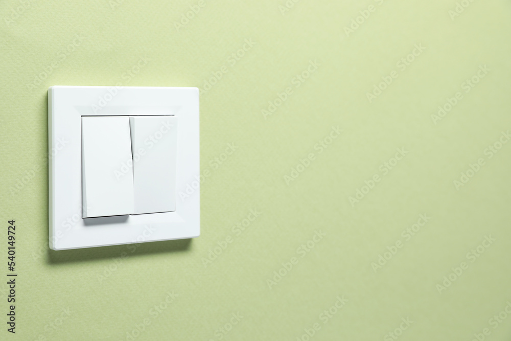 Modern plastic light switch on green background. Space for text Modern plastic light switch on green background. Space for text