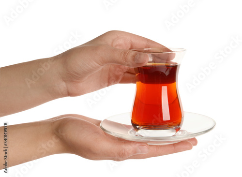 Woman holding glass of traditional Turkish tea with saucer on white background, closeup