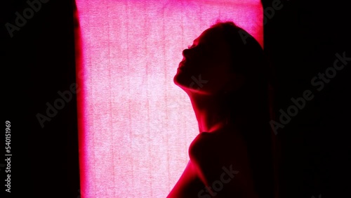 Beautiful young female model posing in front of red light photo