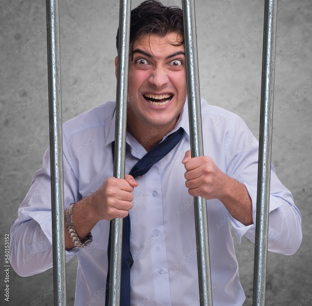 Young businessman behind the bars in prison Young businessman behind the bars in prison